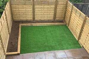 Backyard in South East London with green artificial grass and wooden fencing