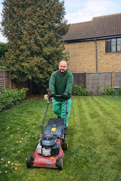 gardening-worker-urban-gardeners Gardening worker mowing lawn in a garden
